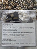 A knitting kit display featuring a ball of Lanas Stop Seal yarn and a ball of Patons Classic Wool Worsted yarn, with a printed mitten pattern. The display has text outlining the yarn and pattern details.