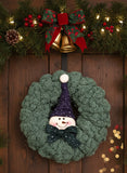Decorative wreath with a snowman face on a wooden door surrounded by Christmas decorations.