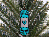 Decorative ornament shaped like a skein of yarn with a heart on a Christmas tree.