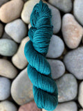 Teal skein of yarn on a bed of pebbles